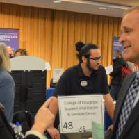 Faculty and an alumnus talking to one another at the Academic Major Fair.